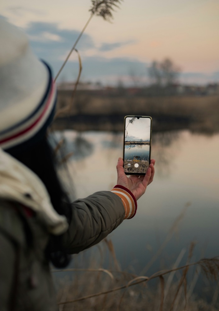 Creator photographing a sunset over a lake on a phone
