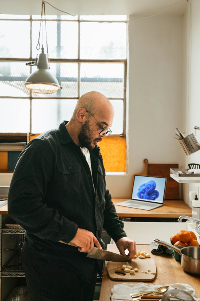 Creator cooking at home with a laptop open in the background