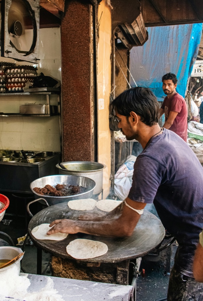 Street food vendor preparing flatbread at a market stall